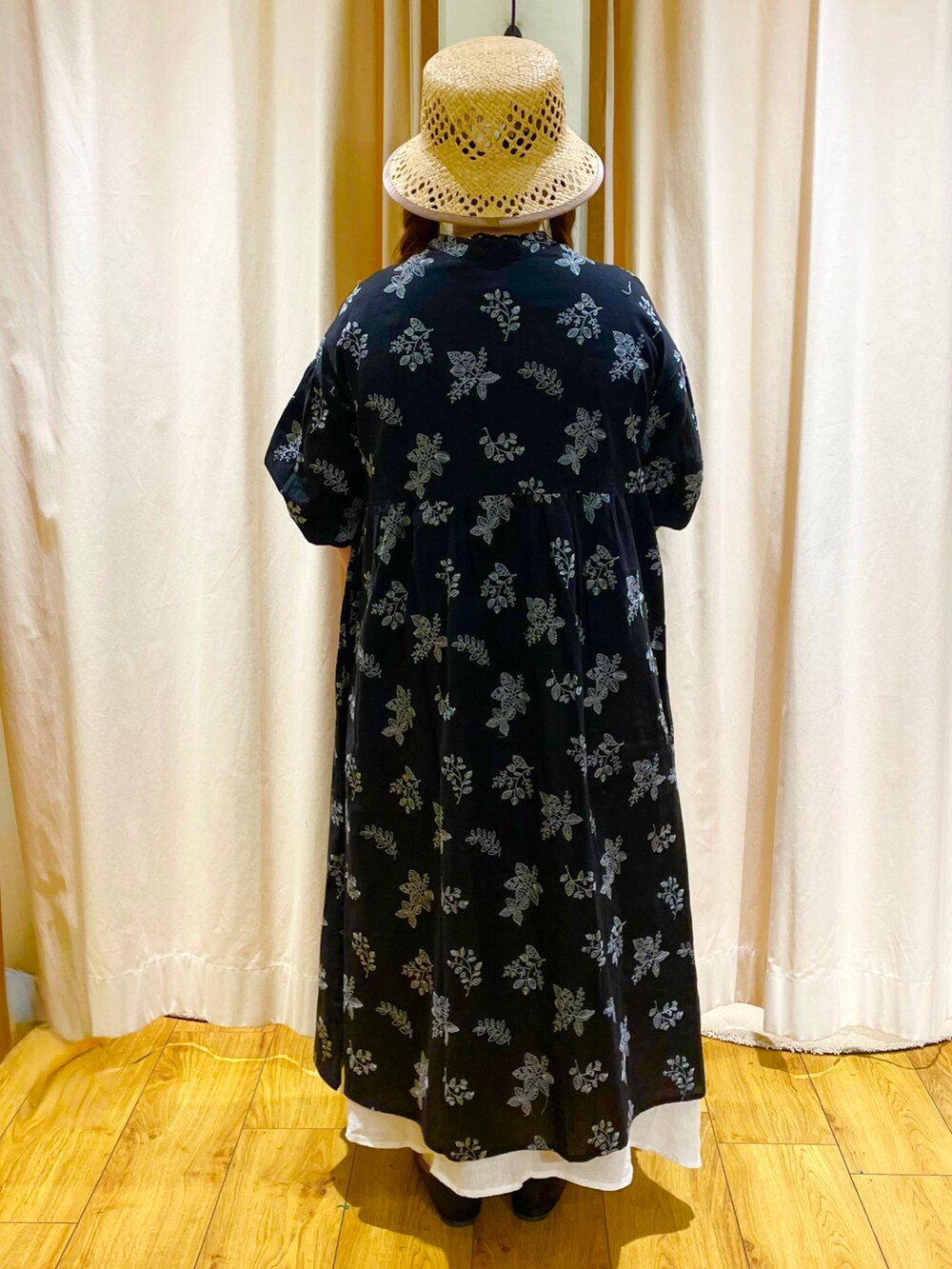 ブラック系のワンピース、ホワイト系のスカート、ベージュ系のハットを着用したレディースの春コーディネートの2枚目の写真