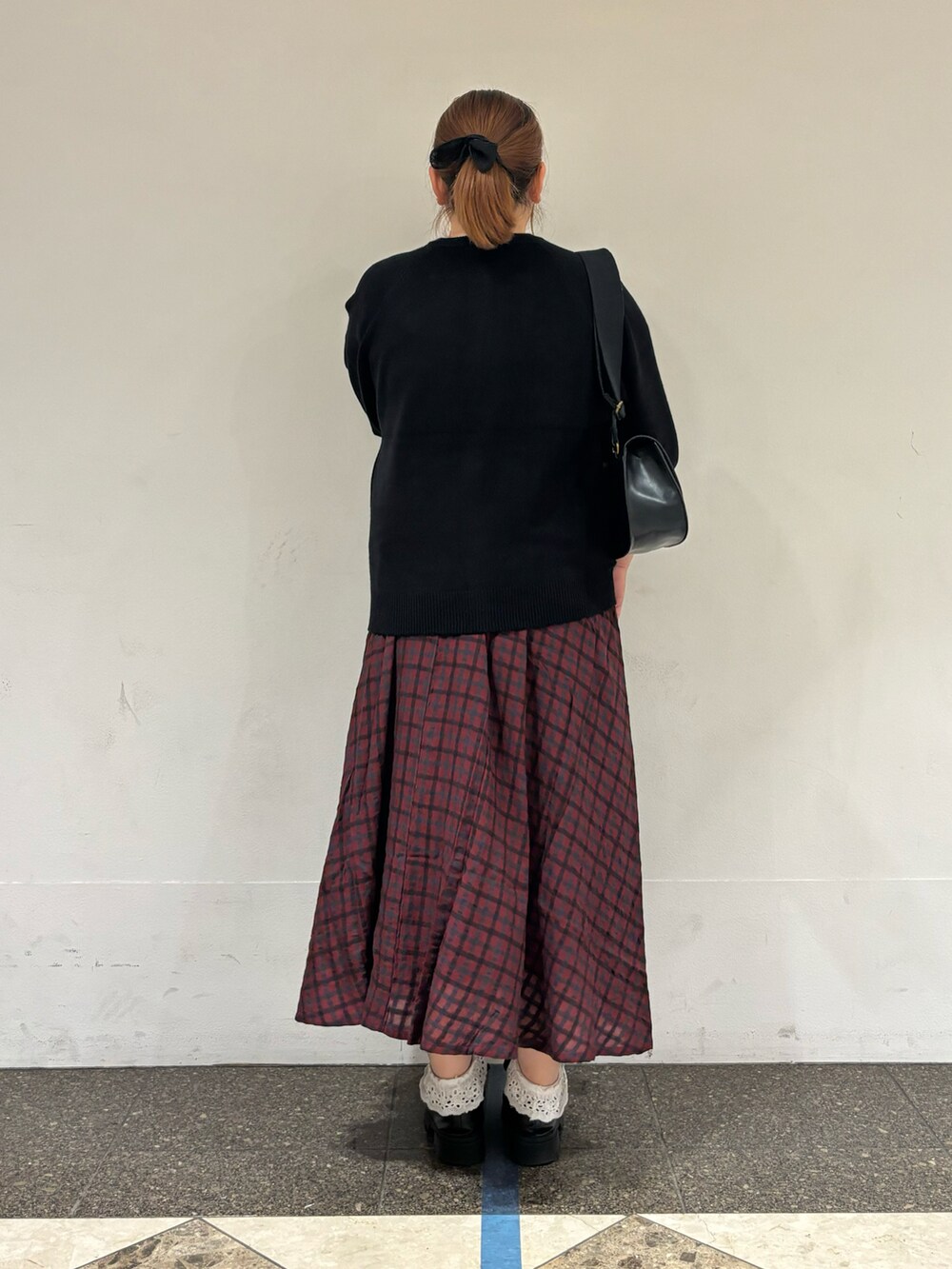 ブラック系のカーディガン/ボレロ、レッド系のスカート、ブラック系のハンドバッグを着用したレディースの秋コーディネートの3枚目の写真