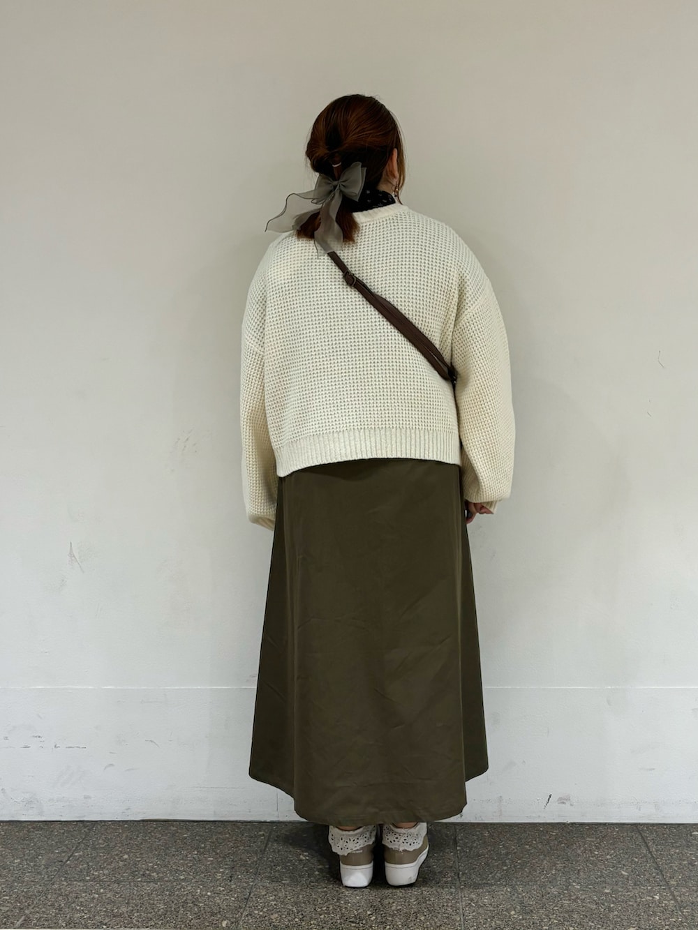 グリーン系のワンピース、ブラウン系のハンドバッグを着用したレディースの冬コーディネートの3枚目の写真