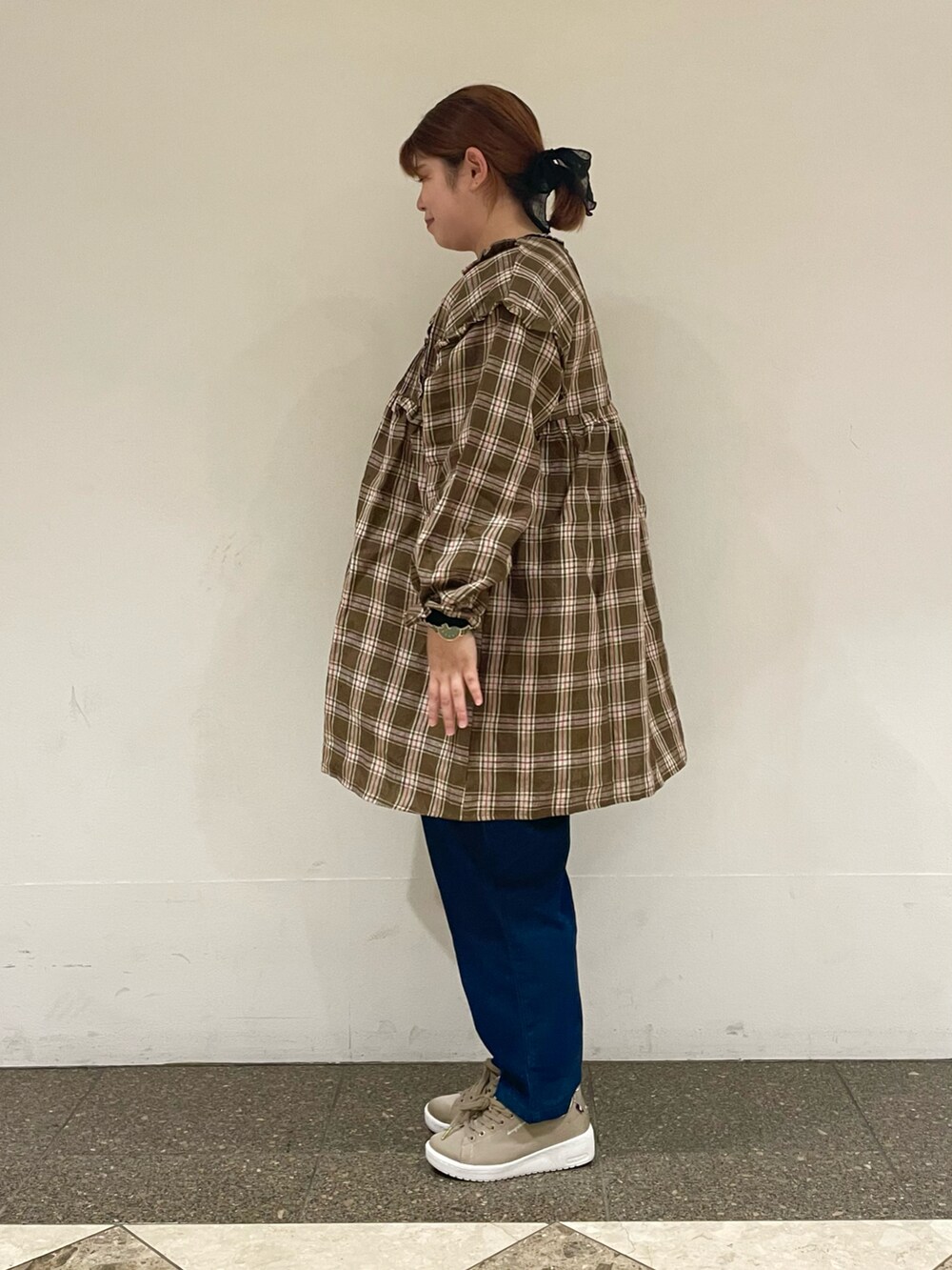 グリーン系のチュニック、ブルー系のデニムパンツ、ブラック系のハンドバッグを着用したレディースの秋コーディネートの2枚目の写真