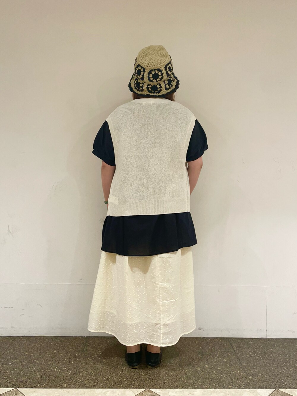 ブラック系のチュニック、ホワイト系のベスト、ホワイト系のスカートを着用したレディースの秋コーディネートの3枚目の写真