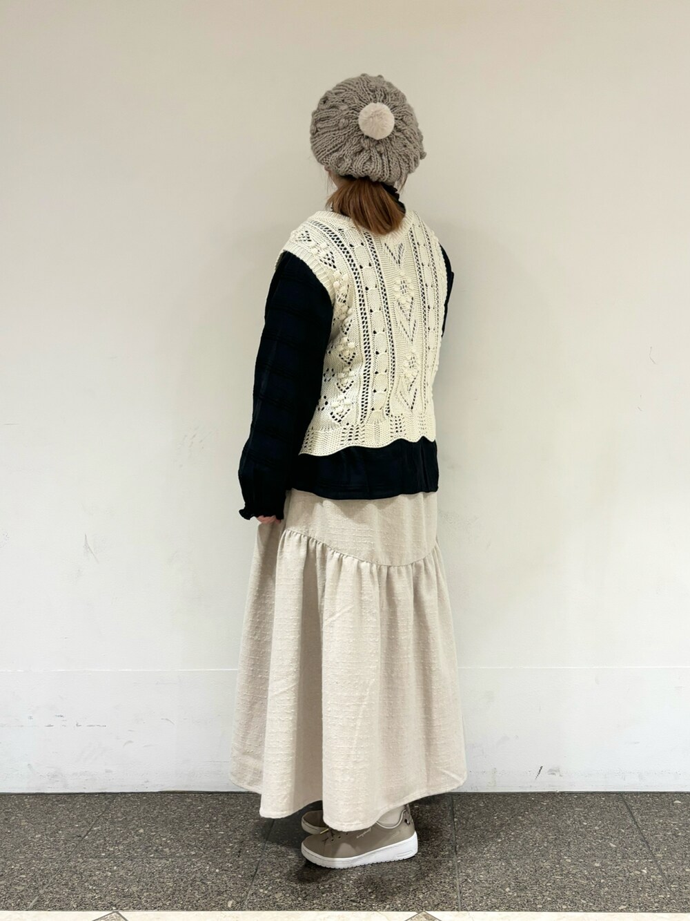 ホワイト系のベスト、ホワイト系のスカート、ブラウン系のハットを着用したレディースの冬コーディネートの2枚目の写真