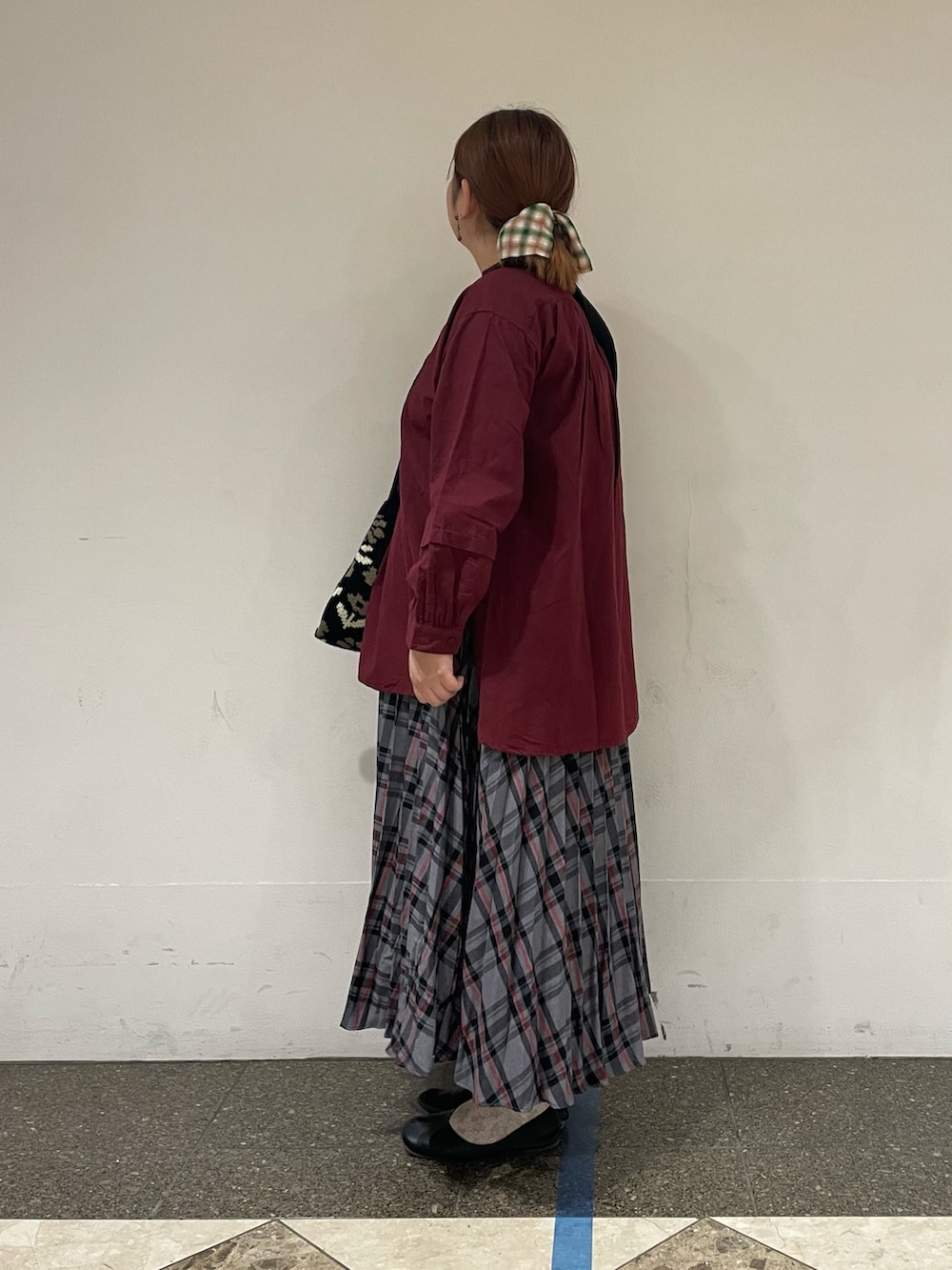 レッド系のチュニック、グレー系のスカート、ブラック系のハンドバッグを着用したレディースの秋コーディネートの2枚目の写真