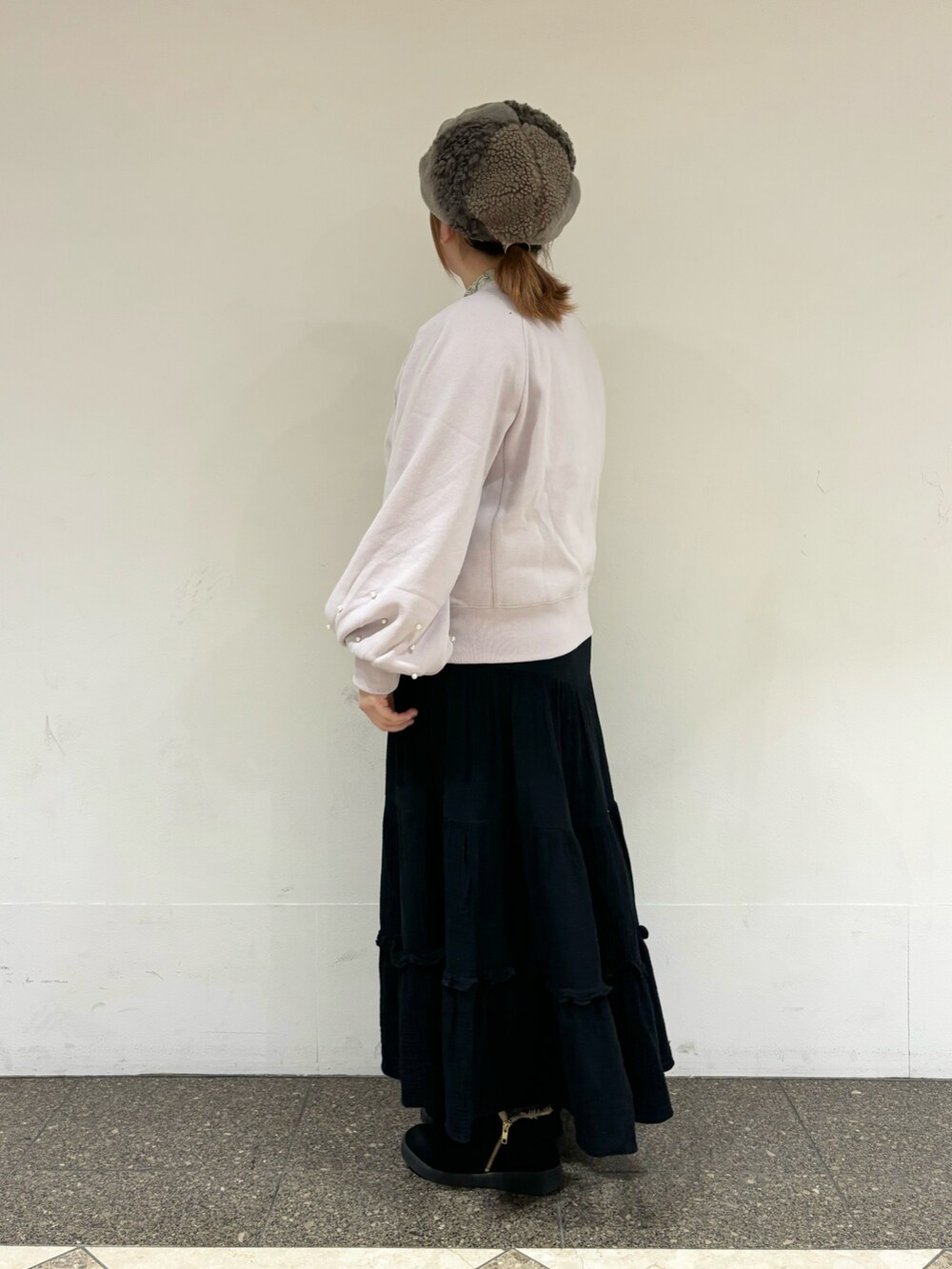 ピンク系のTシャツ/カットソー、ブラック系のスカート、ブラウン系のハットを着用したレディースの冬コーディネートの2枚目の写真