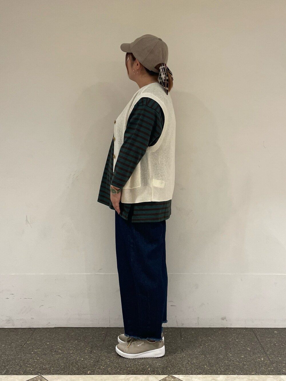 グリーン系のTシャツ/カットソー、ホワイト系のベスト、ブルー系のデニムパンツを着用したレディースの秋コーディネートの2枚目の写真