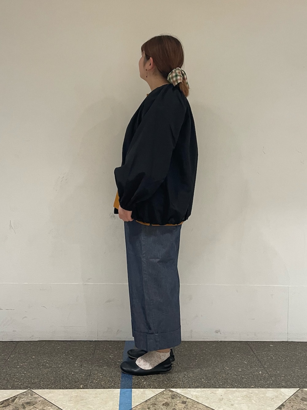 イエロー系のTシャツ/カットソー、ブラック系のブルゾン、ブルー系のデニムパンツを着用したレディースの秋コーディネートの2枚目の写真