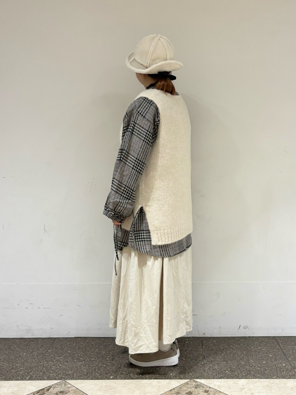 ホワイト系のベスト、ホワイト系のチュニック、ベージュ系のスカートを着用したレディースの冬コーディネートの2枚目の写真