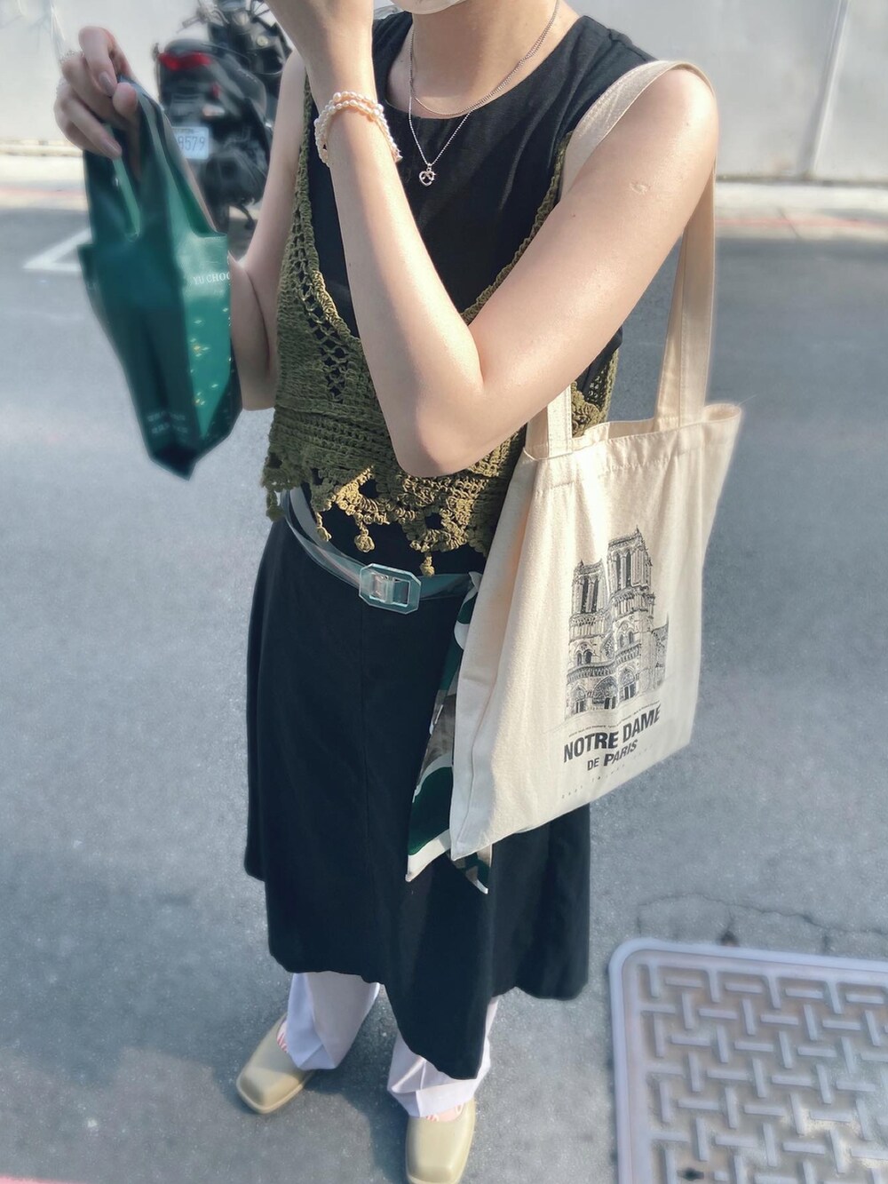 ブラック系のジャンパースカート、グリーン系のスマホケース/カバーを着用したレディースの夏コーディネートの2枚目の写真