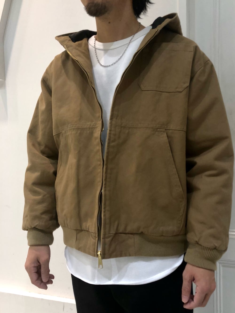 ベージュ系のブルゾン、ホワイト系のTシャツ/カットソー、ブラック系のデニムパンツを着用したメンズの冬コーディネートの2枚目の写真