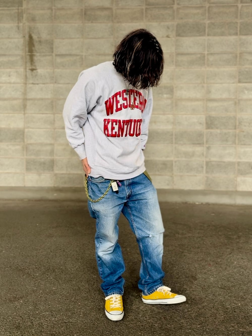 イエロー系のスニーカー、グレー系のスウェット、ブルー系のデニムパンツを着用したメンズの冬コーディネートの2枚目の写真