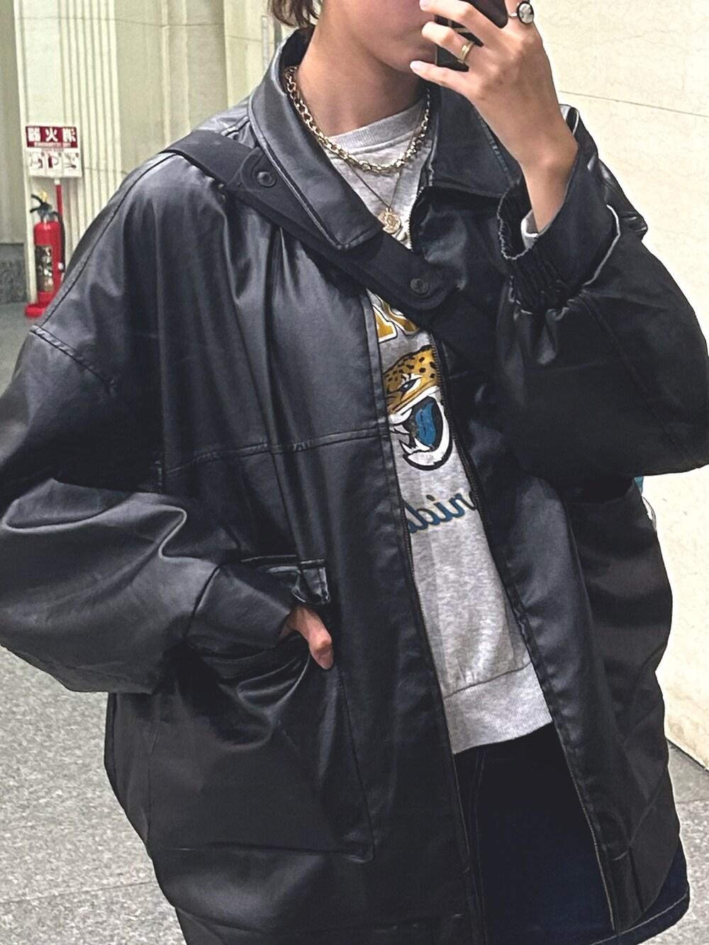 ブラック系のライダースジャケット、ブルー系のデニムスカート、ブラック系のブーツを着用したレディースの秋コーディネートの2枚目の写真