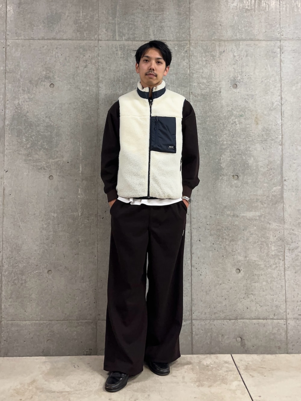 ブラウン系のスウェット、ホワイト系のダウンベスト、ブラウン系のその他パンツを着用したメンズの冬コーディネートの3枚目の写真