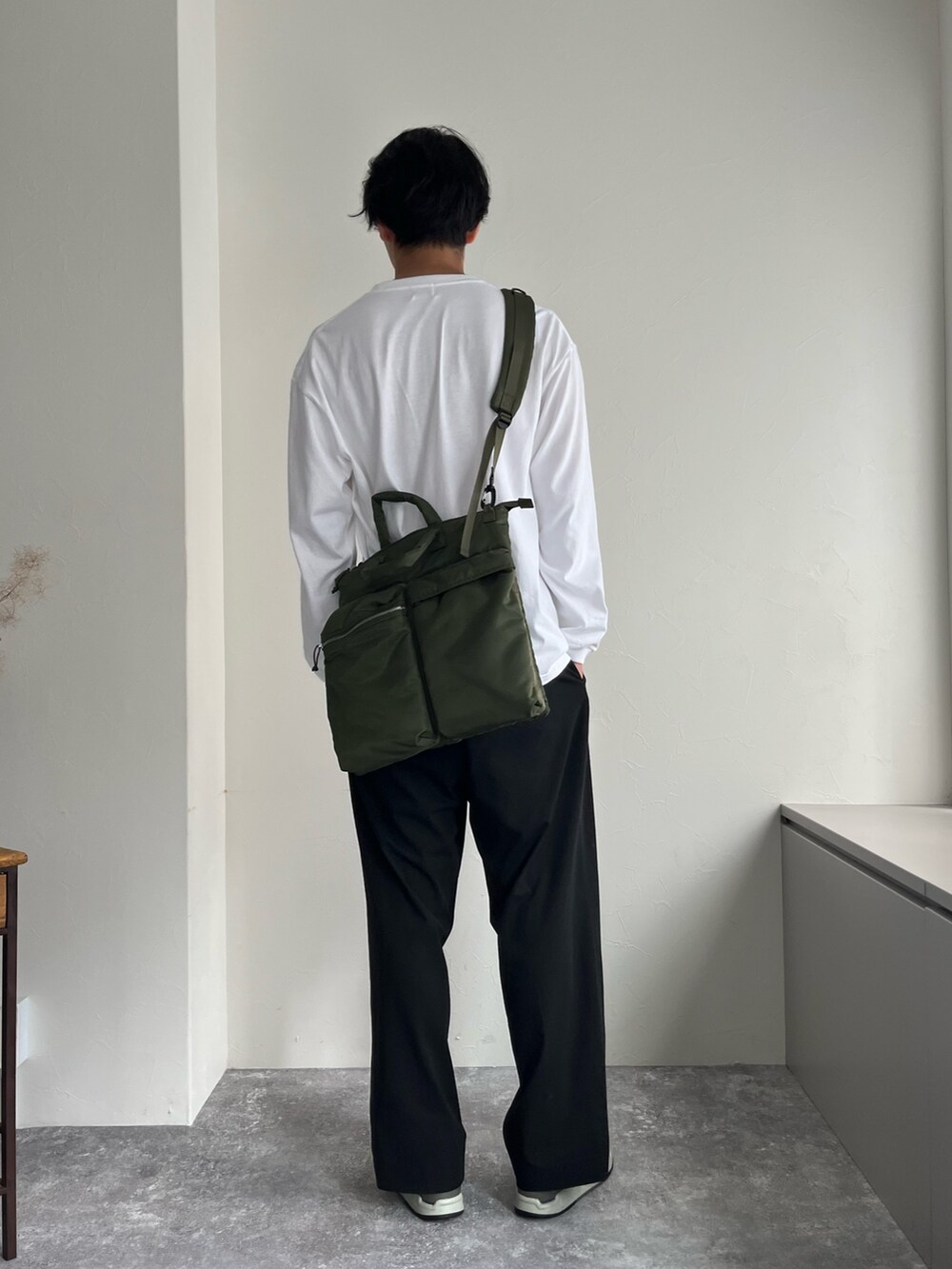 グリーン系のショルダーバッグ、ブラック系のスラックス、ホワイト系のTシャツ/カットソーを着用したメンズの夏コーディネートの3枚目の写真