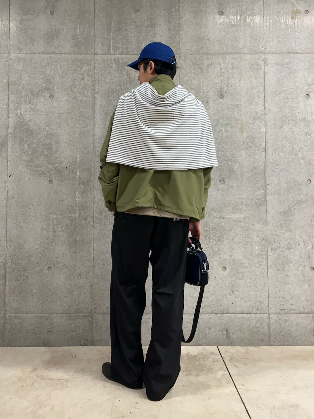 ブルー系のショルダーバッグ、ホワイト系のTシャツ/カットソー、グリーン系のブルゾンを着用したメンズの秋コーディネートの4枚目の写真