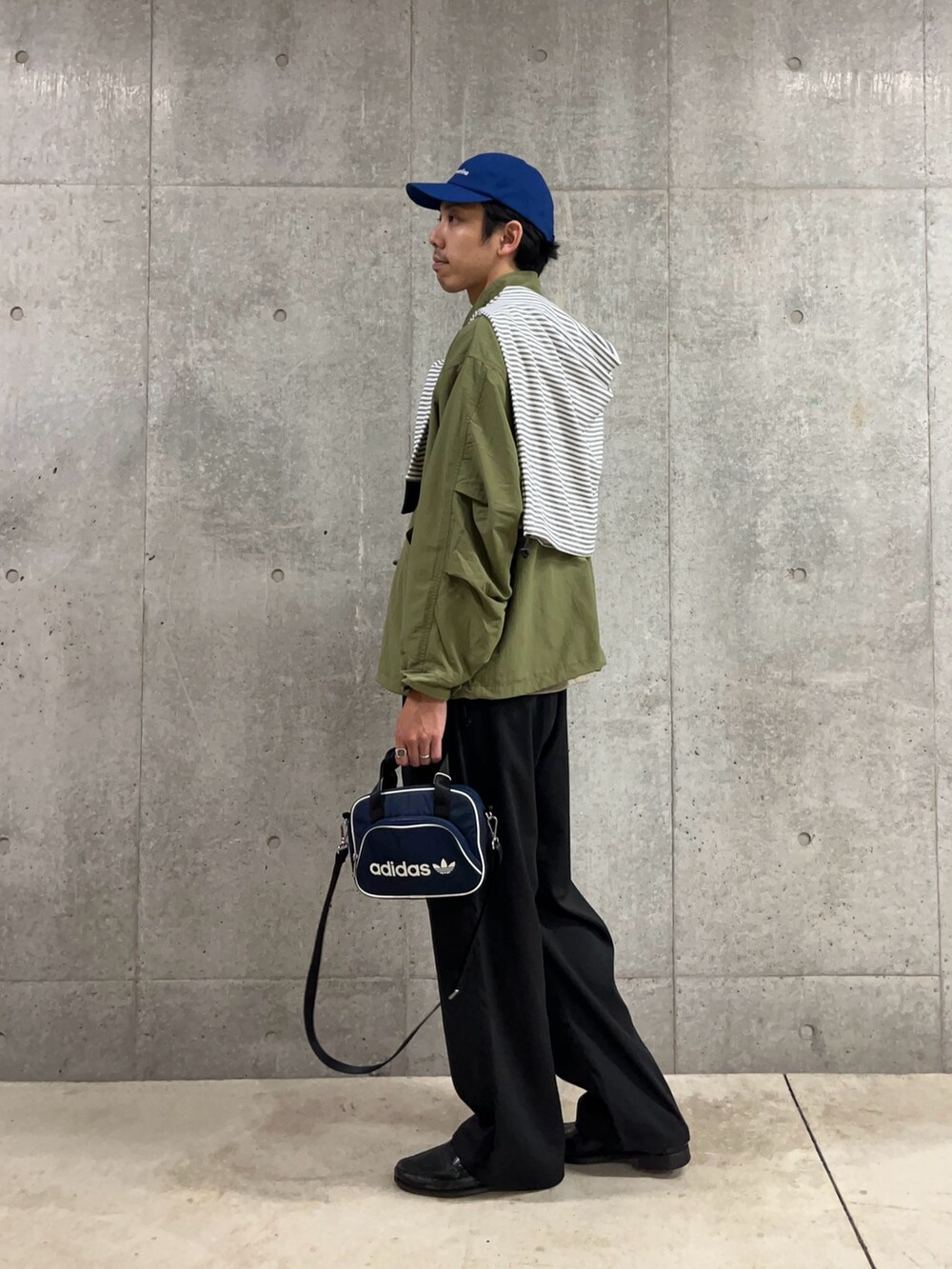 ブルー系のショルダーバッグ、ホワイト系のTシャツ/カットソー、グリーン系のブルゾンを着用したメンズの秋コーディネートの3枚目の写真