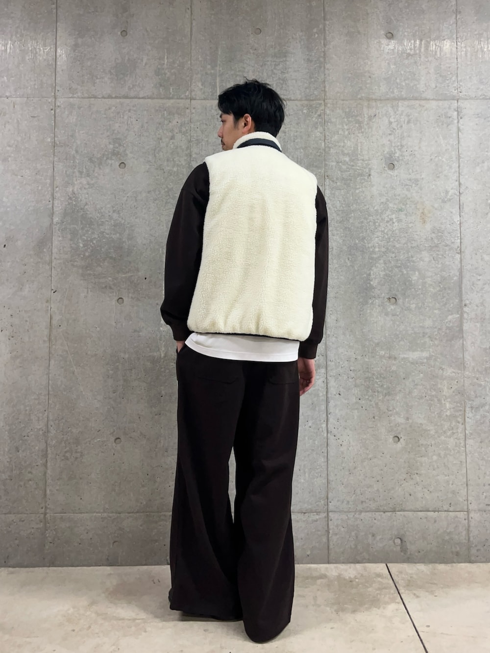 ブラウン系のスウェット、ホワイト系のダウンベスト、ブラウン系のその他パンツを着用したメンズの冬コーディネートの5枚目の写真