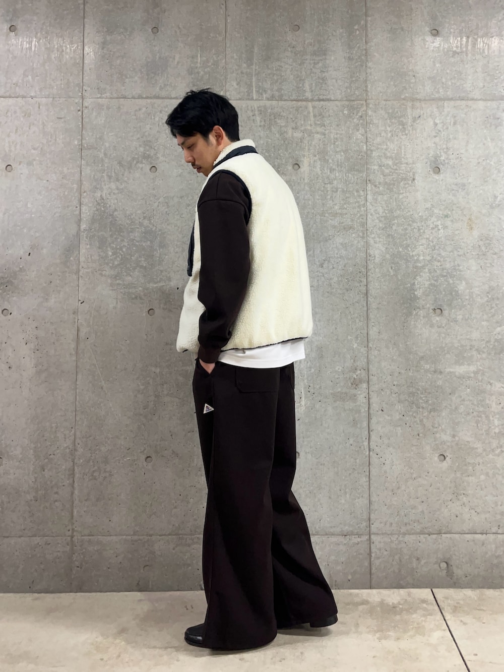 ブラウン系のスウェット、ホワイト系のダウンベスト、ブラウン系のその他パンツを着用したメンズの冬コーディネートの4枚目の写真