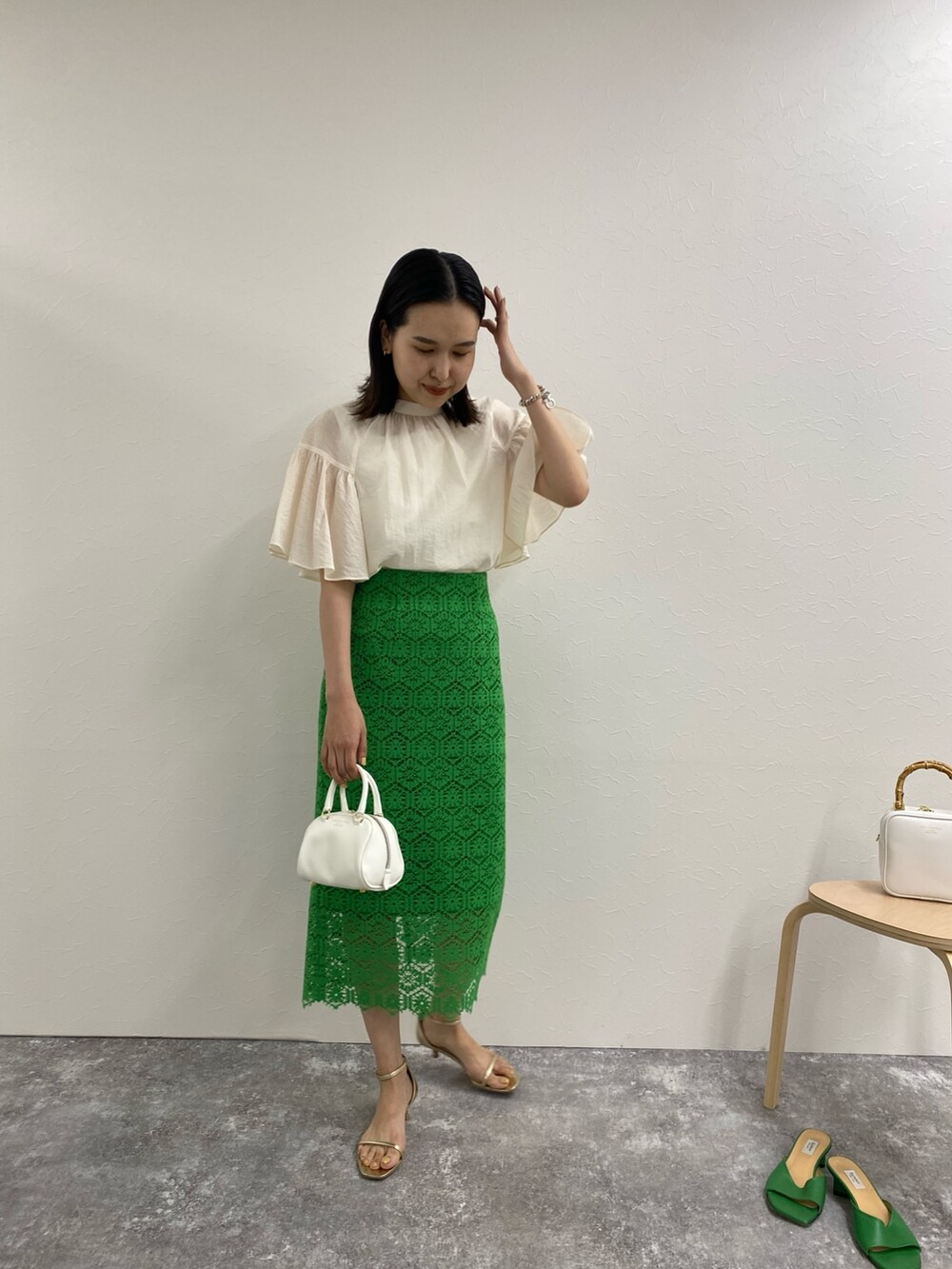 グリーン系のスカート、ホワイト系のシャツ/ブラウス、ゴールド系のサンダルを着用したレディースの春コーディネートの2枚目の写真