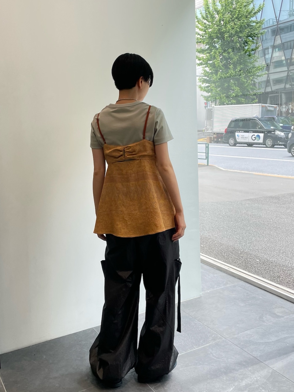 オレンジ系のキャミソール、ブラック系のカーゴパンツ、グリーン系のTシャツ/カットソーを着用したレディースの春コーディネートの3枚目の写真