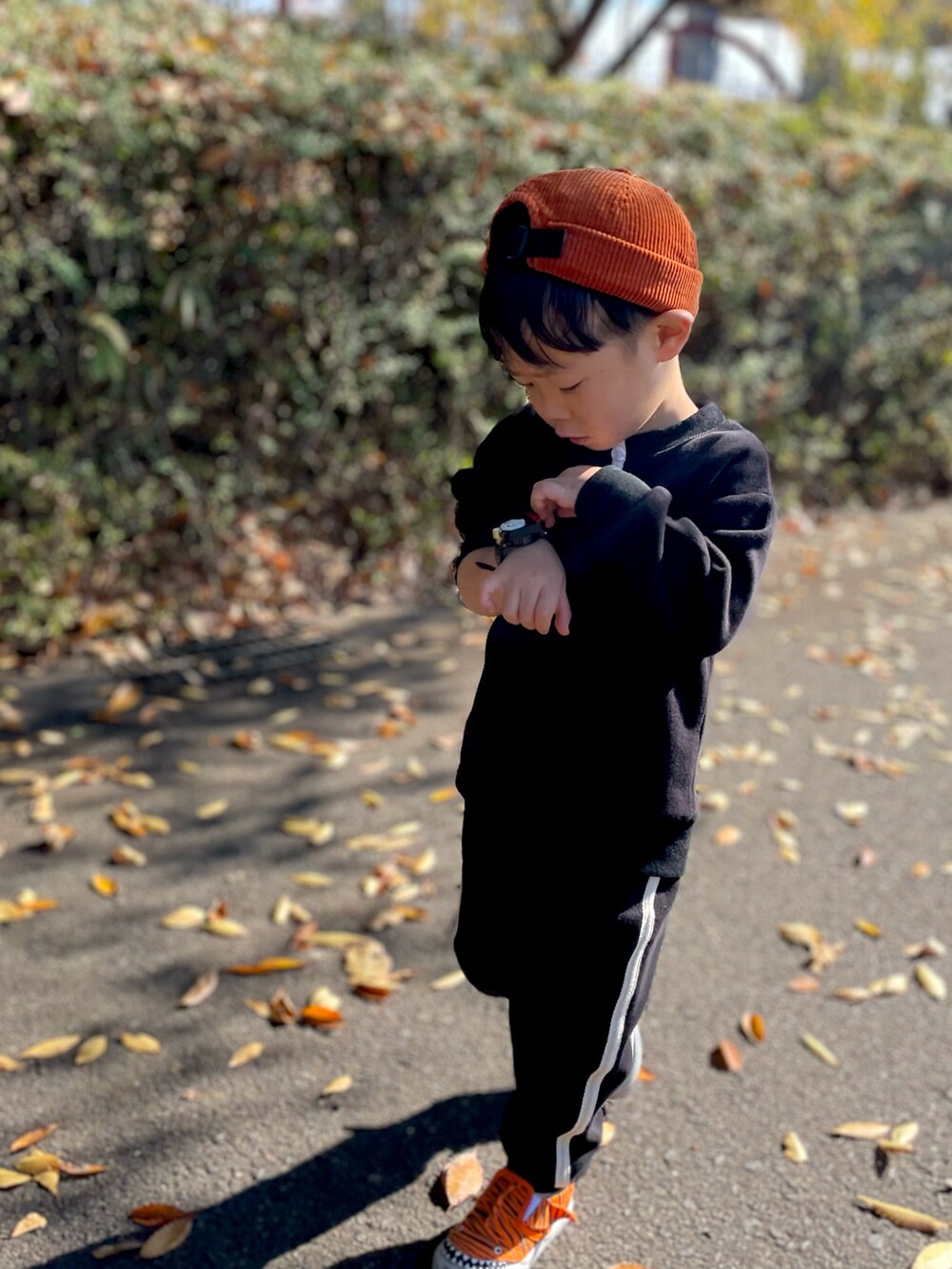 ブラック系のスニーカー、グリーン系の帽子を着用したキッズの秋コーディネートの2枚目の写真