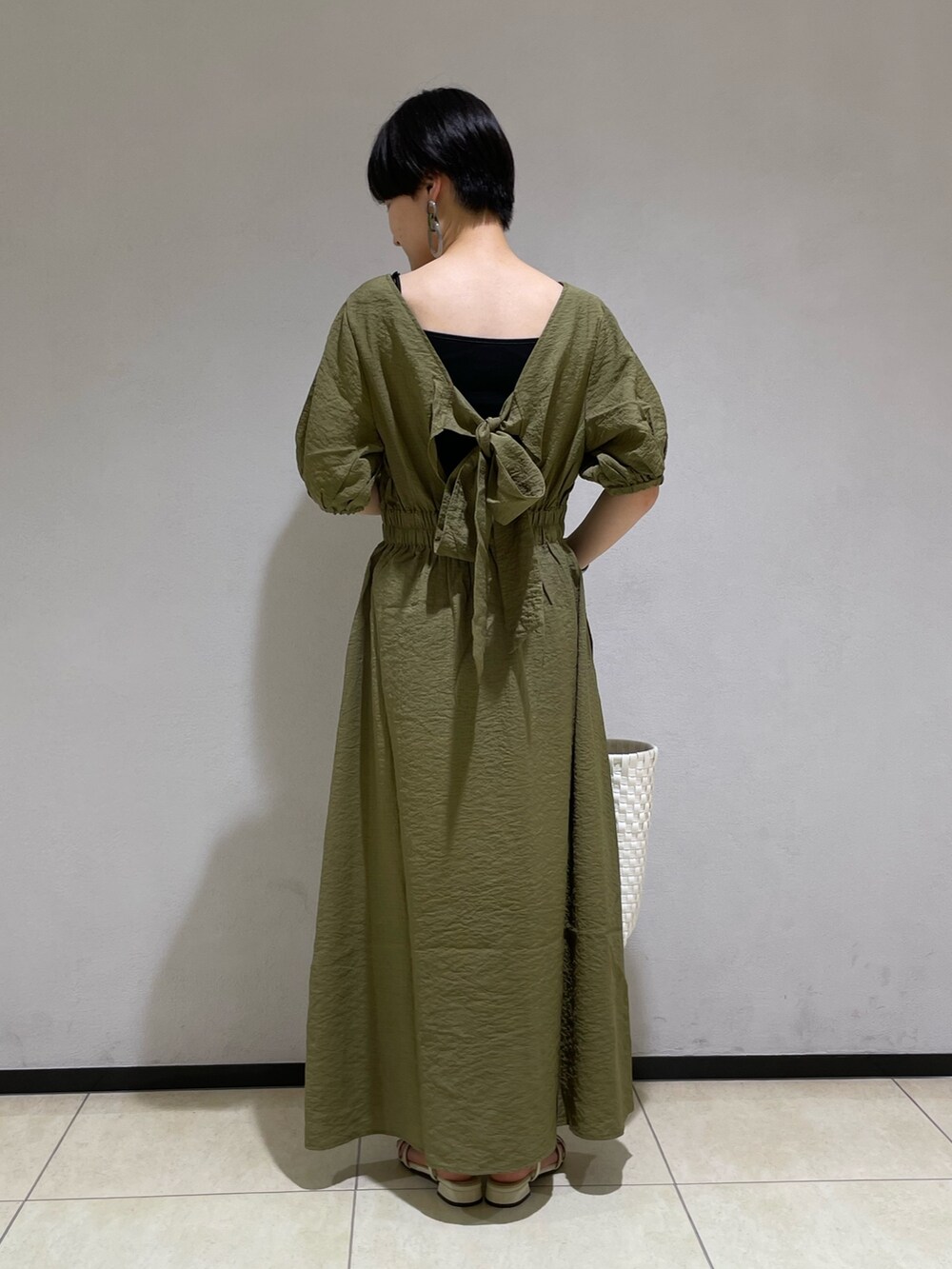 グリーン系のワンピース、ホワイト系のかごバッグ、ホワイト系のサンダルを着用したレディースの夏コーディネートの3枚目の写真