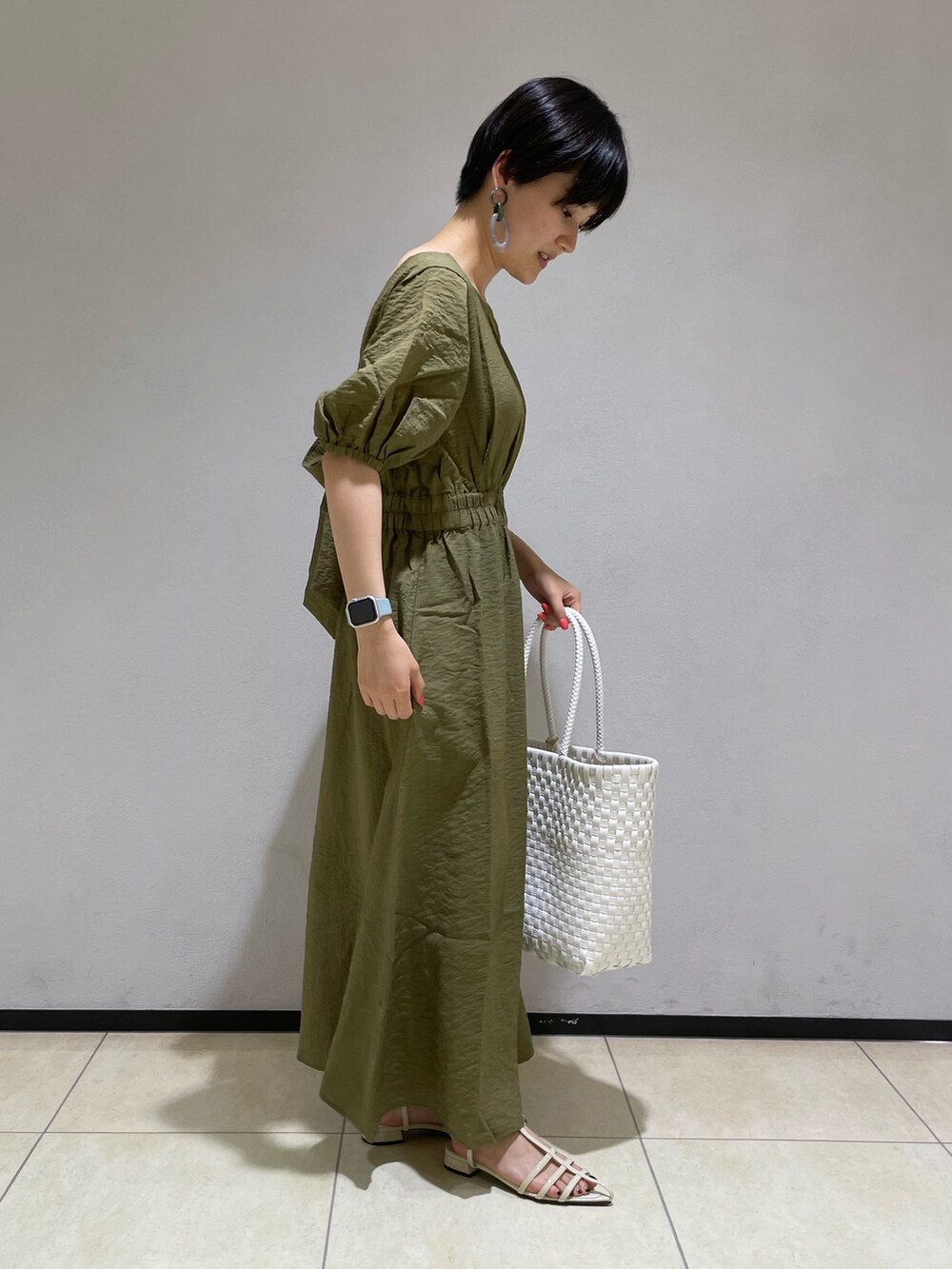 グリーン系のワンピース、ホワイト系のかごバッグ、ホワイト系のサンダルを着用したレディースの夏コーディネートの2枚目の写真