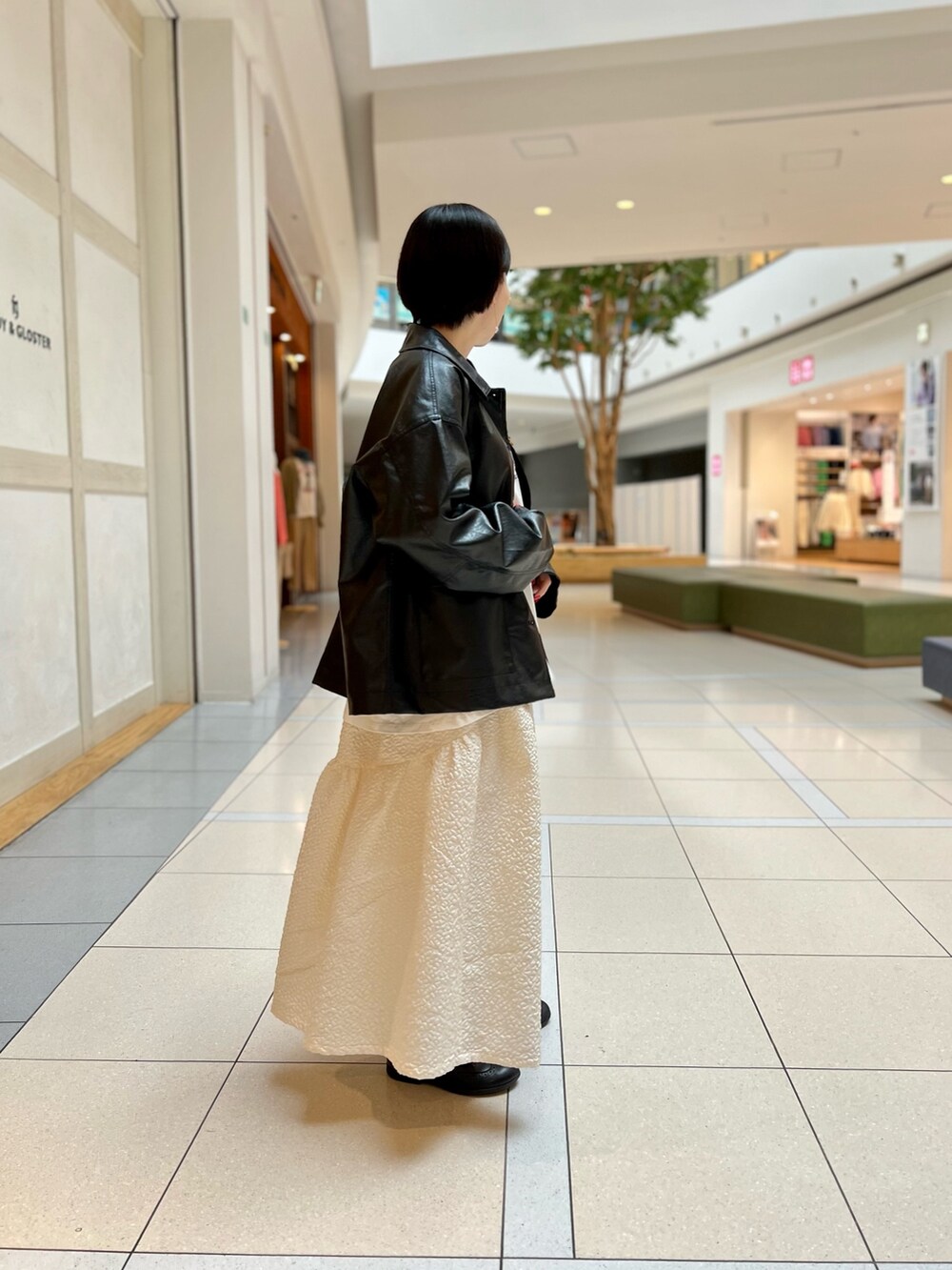 ブラック系のブルゾン、ホワイト系のスカート、ホワイト系のTシャツ/カットソーを着用したレディースの春コーディネートの2枚目の写真