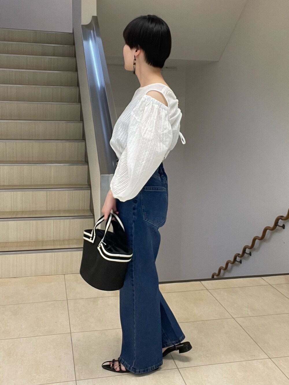ホワイト系のシャツ/ブラウス、ブルー系のデニムパンツ、ブラック系のトートバッグを着用したレディースの春コーディネートの2枚目の写真