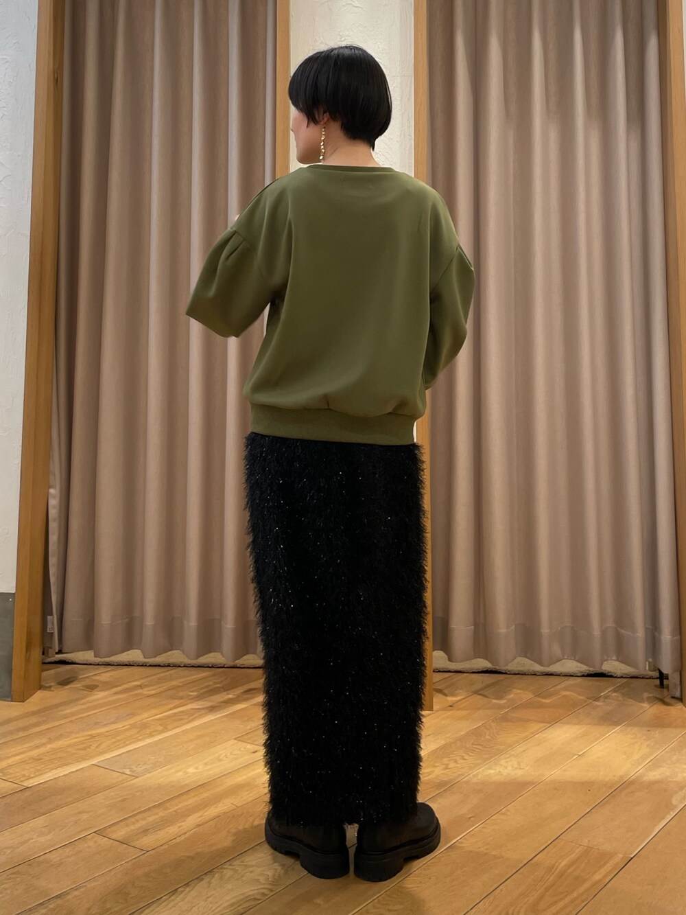 グリーン系のTシャツ/カットソー、ブラック系のスカート、ホワイト系のショルダーバッグを着用したレディースの冬コーディネートの3枚目の写真