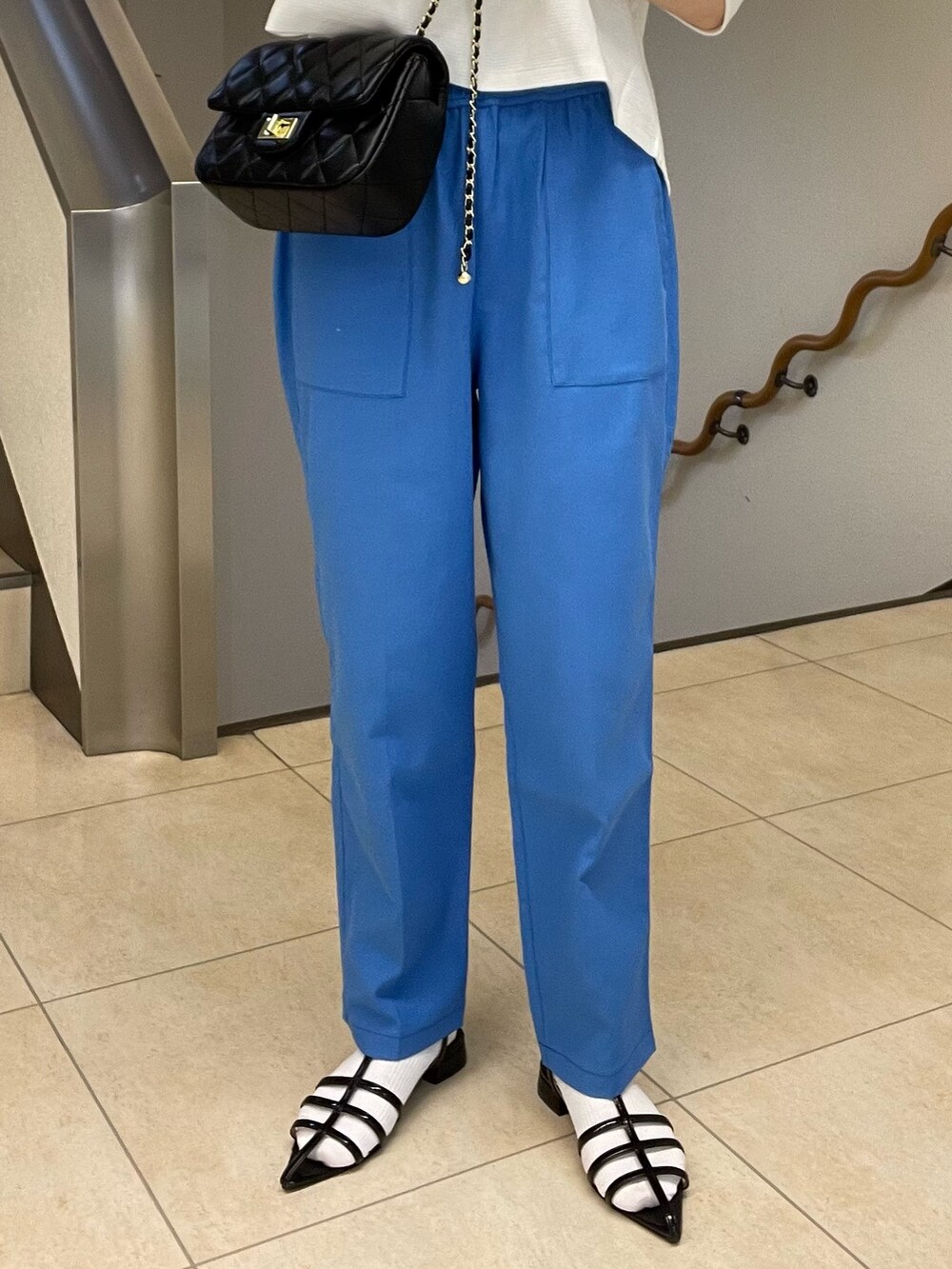 ホワイト系のTシャツ/カットソー、ブルー系のスラックス、ブラック系のショルダーバッグを着用したレディースの春コーディネートの4枚目の写真