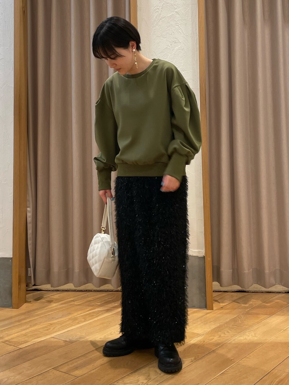 グリーン系のTシャツ/カットソー、ブラック系のスカート、ホワイト系のショルダーバッグを着用したレディースの冬コーディネートの2枚目の写真