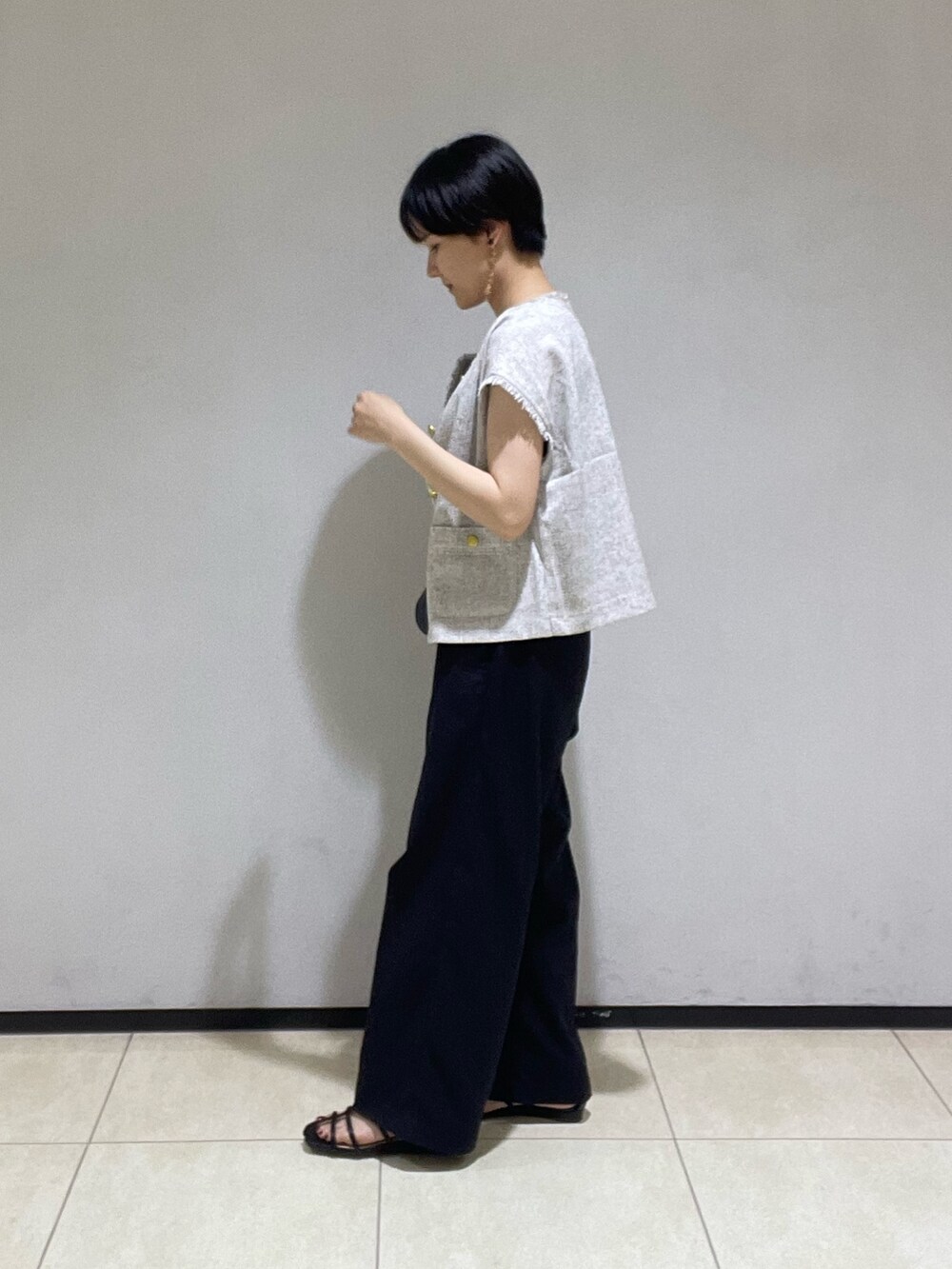 グレー系のシャツ/ブラウス、ブラック系のスラックス、ブラック系のサンダルを着用したレディースの夏コーディネートの2枚目の写真