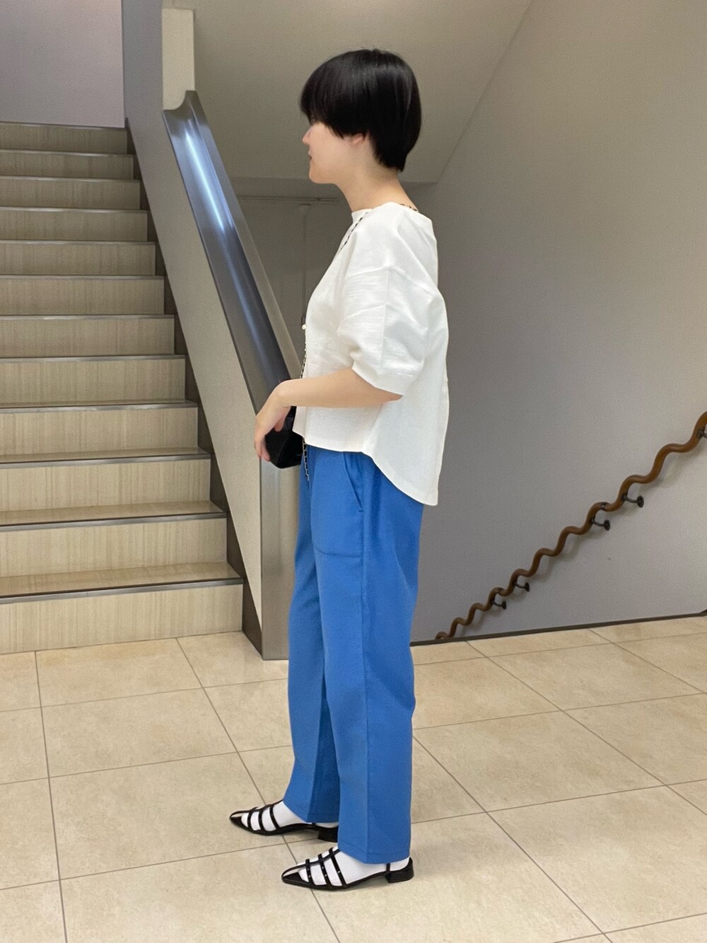 ホワイト系のTシャツ/カットソー、ブルー系のスラックス、ブラック系のショルダーバッグを着用したレディースの春コーディネートの2枚目の写真