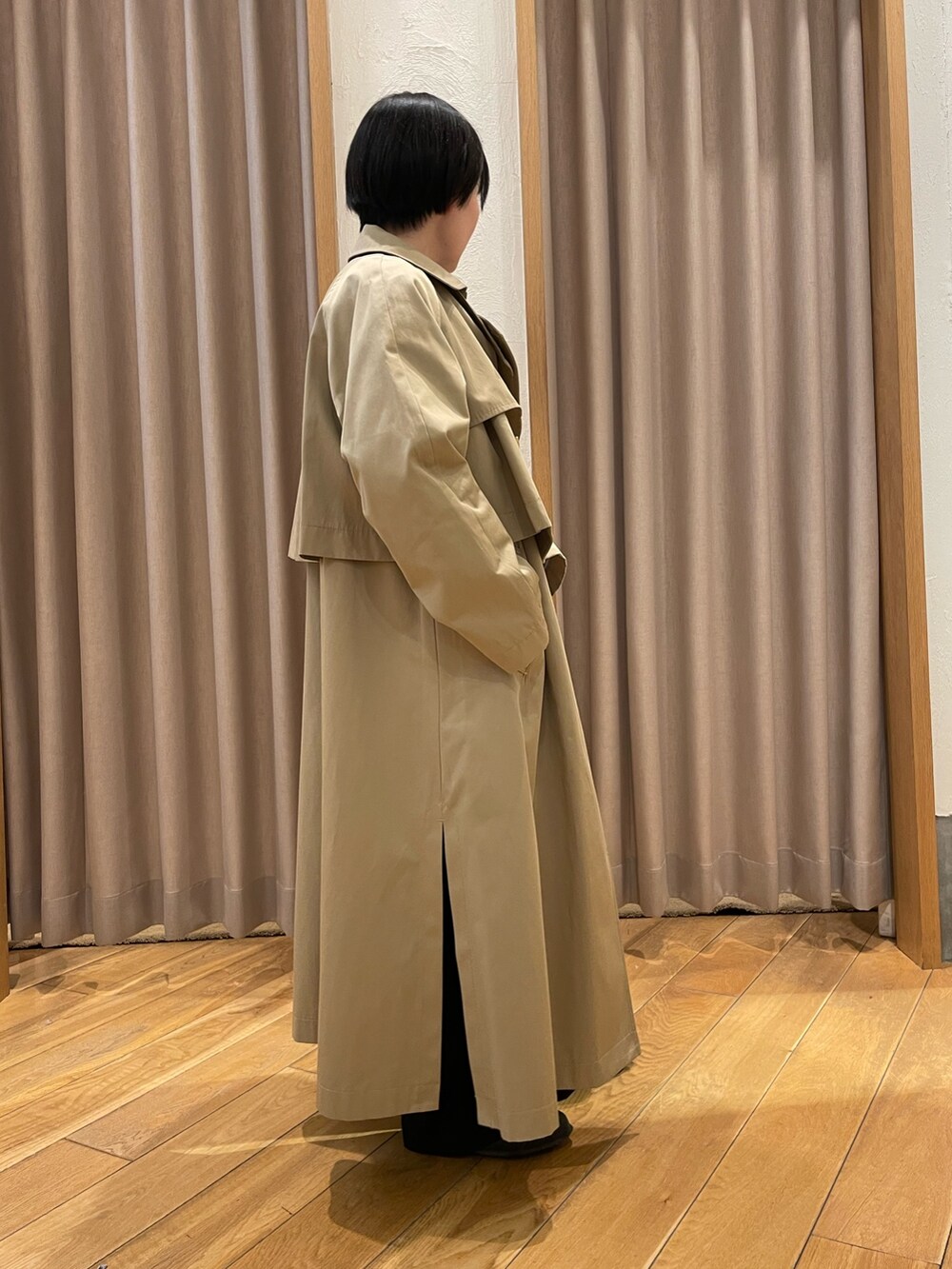 ベージュ系のトレンチコート、ブルー系のシャツ/ブラウス、ブラック系のスラックスを着用したレディースの春コーディネートの2枚目の写真