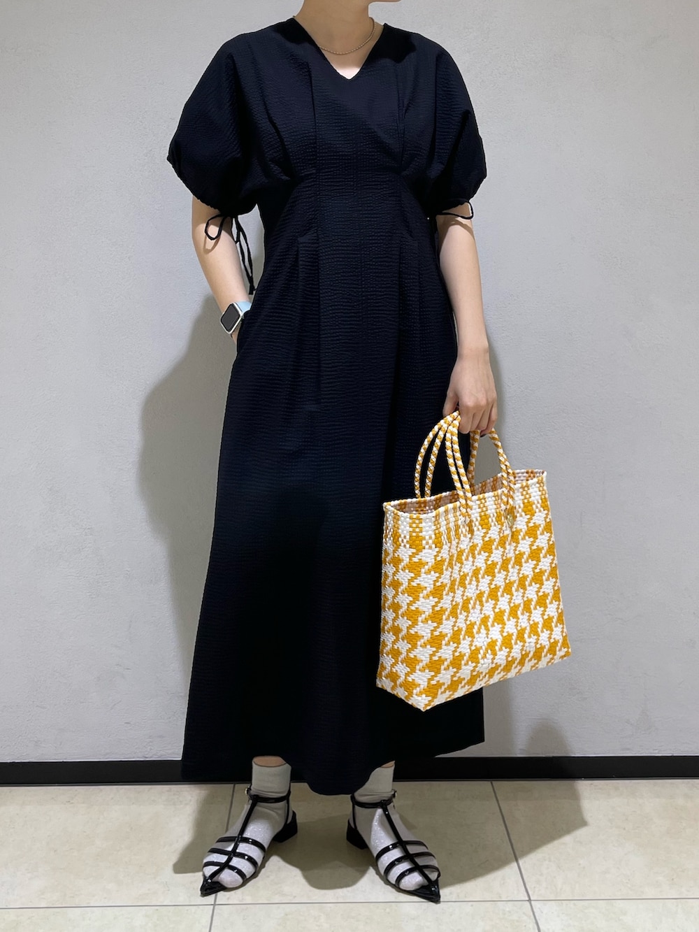 ブラック系のワンピース、イエロー系のトートバッグ、ブラック系のサンダルを着用したレディースの春コーディネートの4枚目の写真
