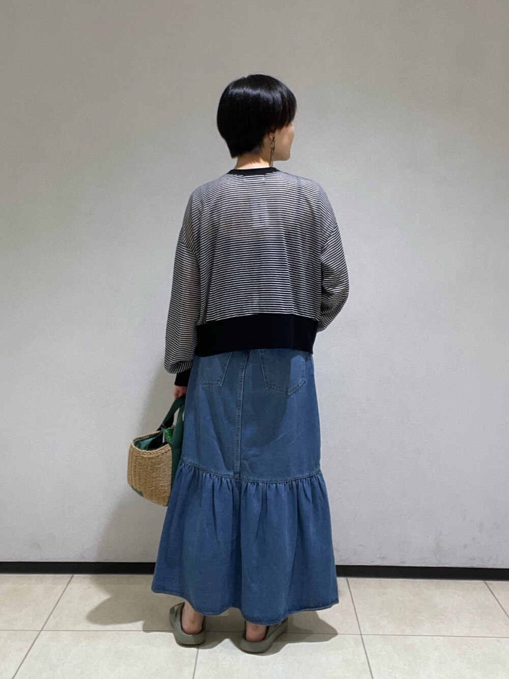 ブラック系のカーディガン/ボレロ、グリーン系のかごバッグ、ブルー系のデニムスカートを着用したレディースの夏コーディネートの3枚目の写真