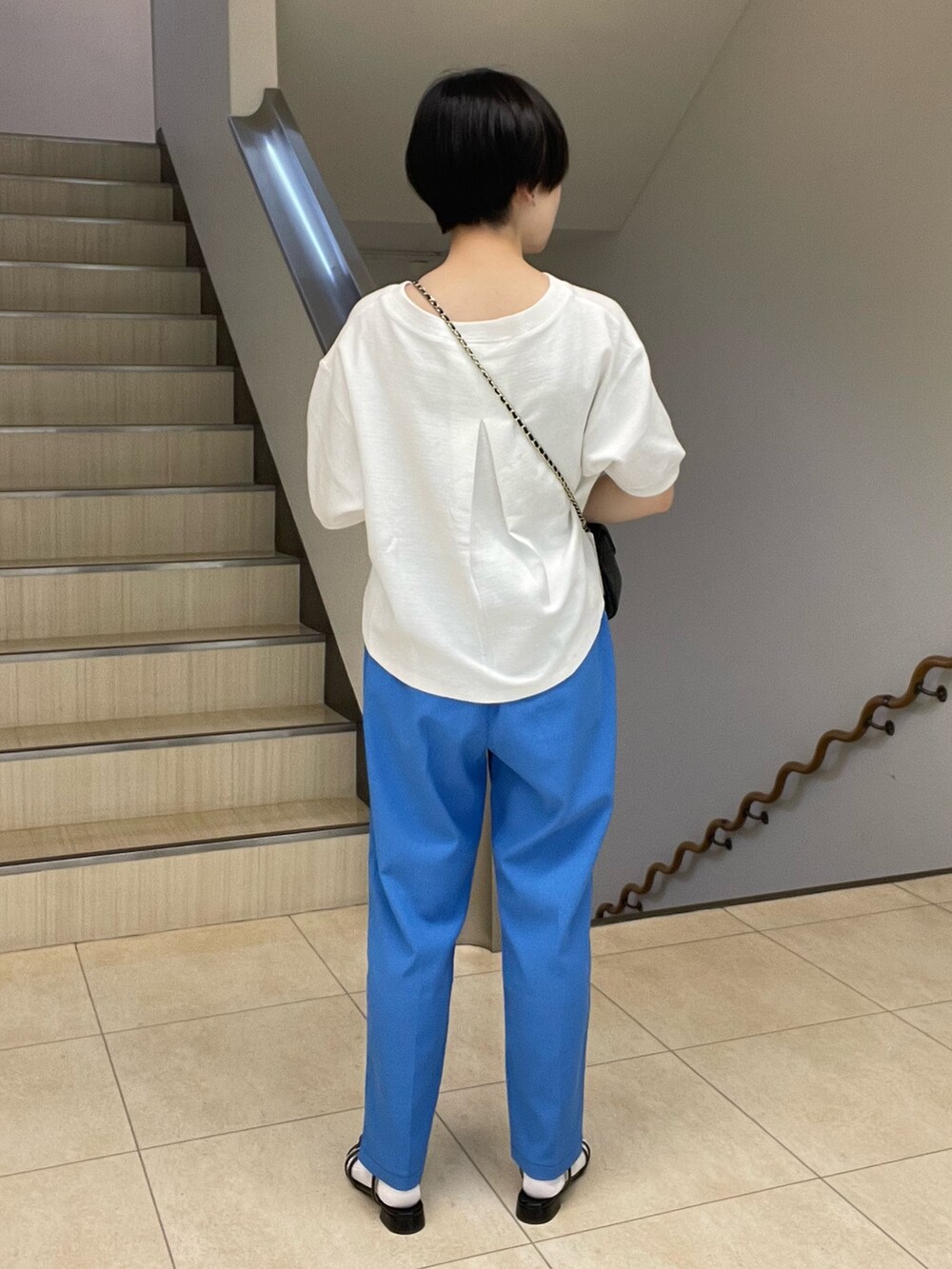 ホワイト系のTシャツ/カットソー、ブルー系のスラックス、ブラック系のショルダーバッグを着用したレディースの春コーディネートの3枚目の写真