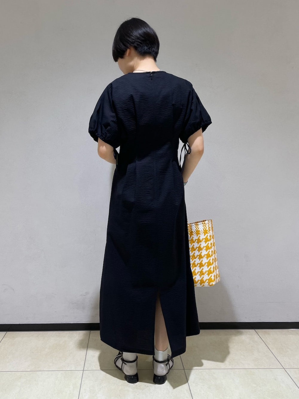 ブラック系のワンピース、イエロー系のトートバッグ、ブラック系のサンダルを着用したレディースの春コーディネートの3枚目の写真