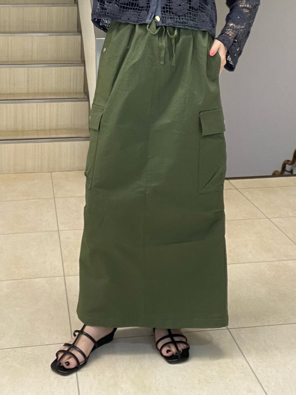 グレー系のカーディガン/ボレロ、グリーン系のスカート、ブラック系のサンダルを着用したレディースの夏コーディネートの5枚目の写真