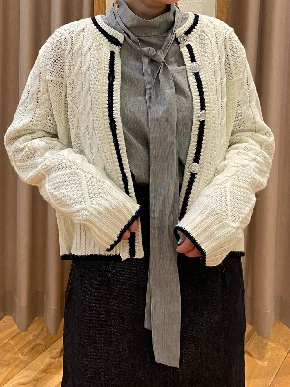 ホワイト系のカーディガン/ボレロ、グレー系のシャツ/ブラウス、ブルー系のデニムスカートを着用したレディースの冬コーディネートの4枚目の写真