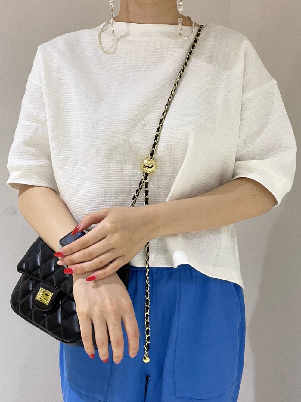 ホワイト系のTシャツ/カットソー、ブルー系のスラックス、ブラック系のショルダーバッグを着用したレディースの春コーディネートの5枚目の写真