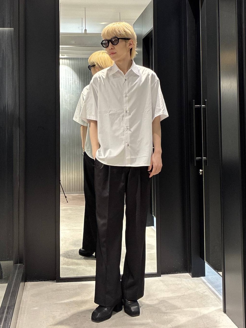 ブラック系のスラックス、ブラック系のサンダル、ホワイト系のニット/セーターを着用したメンズの春コーディネートの3枚目の写真