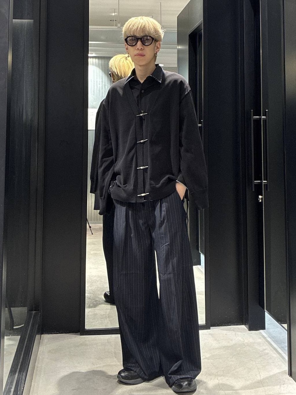 ブラック系のシャツ/ブラウス、ブルー系のスラックス、ブラック系のカーディガン/ボレロを着用したメンズの春コーディネートの2枚目の写真