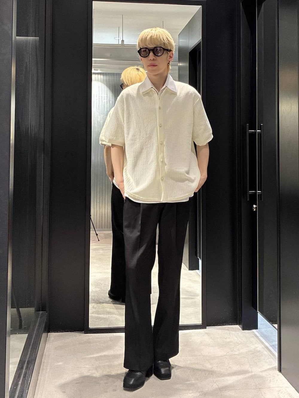 ブラック系のスラックス、ブラック系のサンダル、ホワイト系のニット/セーターを着用したメンズの春コーディネートの2枚目の写真