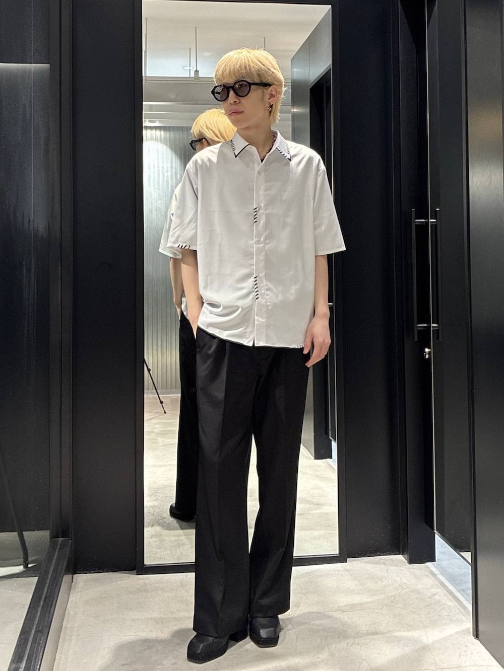 ブラック系のスラックス、ブラック系のサンダル、ホワイト系のシャツ/ブラウスを着用したメンズの春コーディネートの2枚目の写真