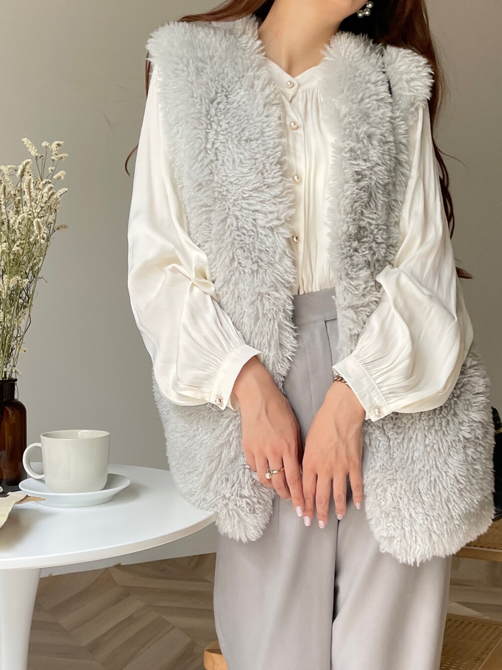 グレー系のベスト、グレー系のスラックス、ブラック系のショルダーバッグを着用したレディースの秋コーディネートの2枚目の写真