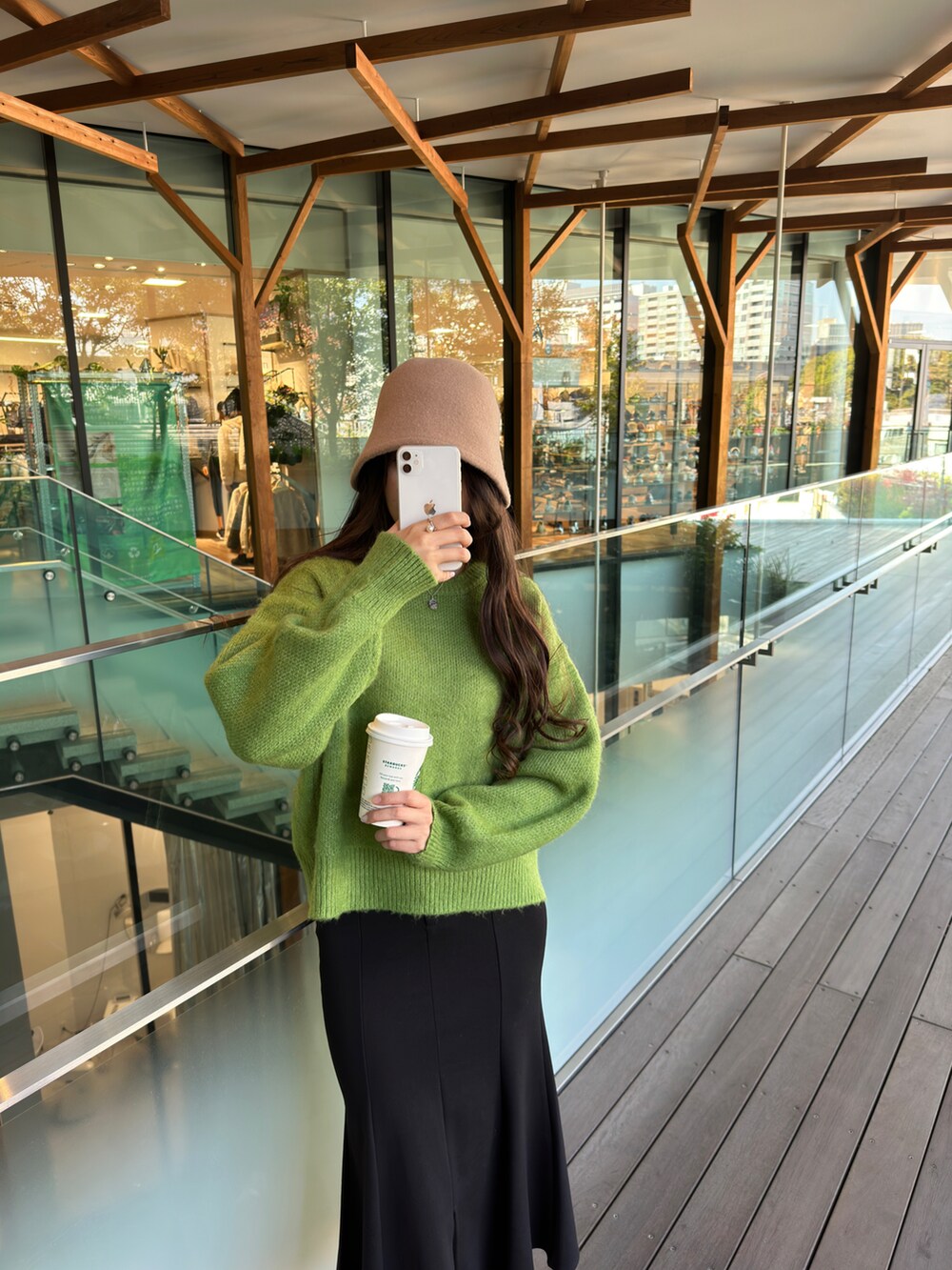 グリーン系のニット/セーター、ブラック系のスカート、ベージュ系のハットを着用したレディースの秋コーディネートの5枚目の写真