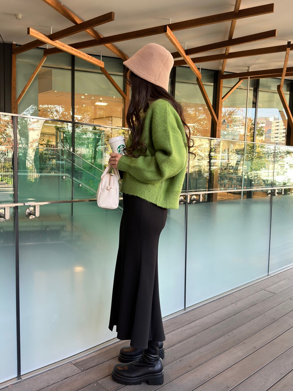 グリーン系のニット/セーター、ブラック系のスカート、ベージュ系のハットを着用したレディースの秋コーディネートの2枚目の写真
