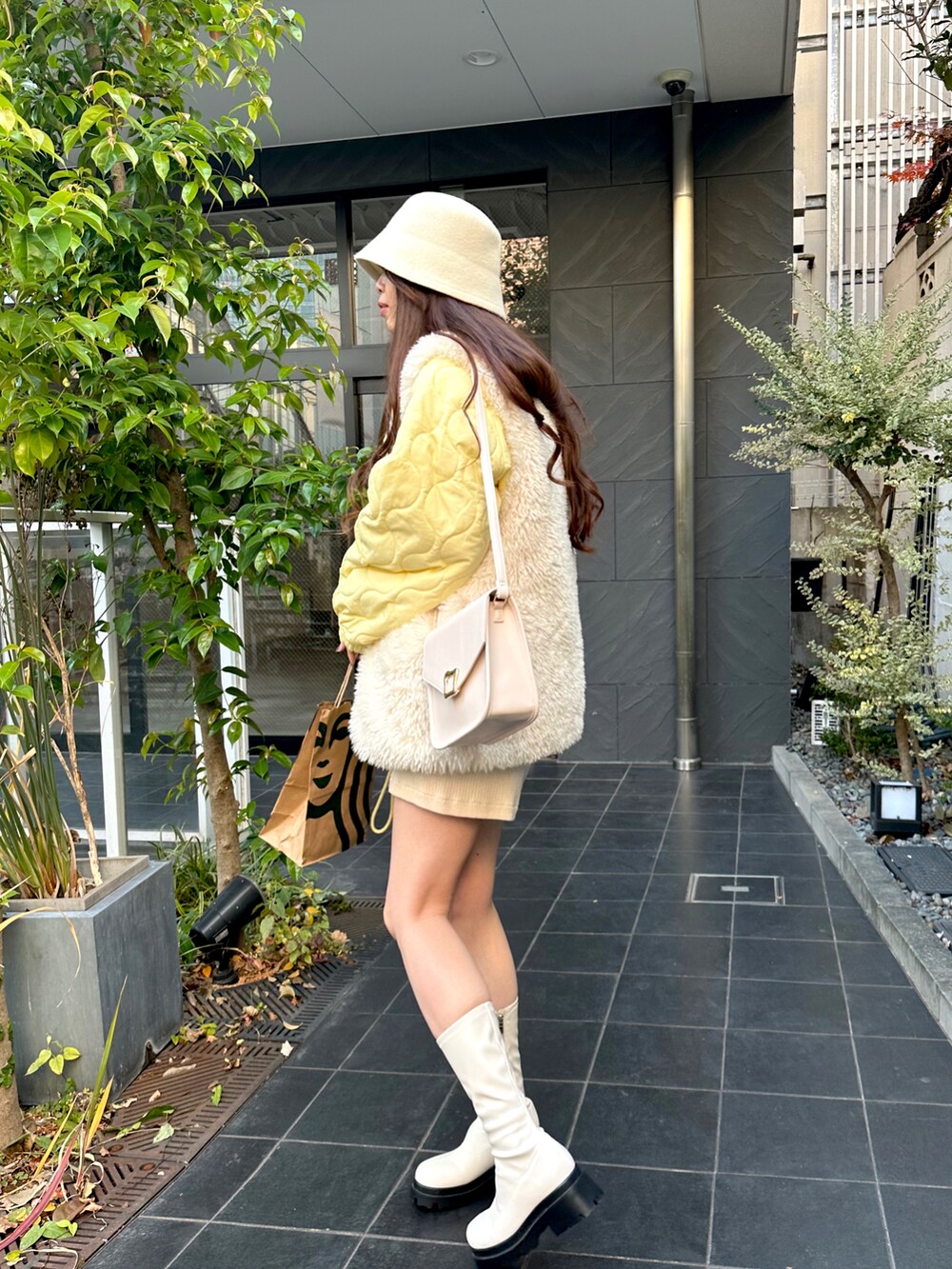 イエロー系のブルゾン、ホワイト系のベスト、ホワイト系のその他パンツを着用したレディースの冬コーディネートの3枚目の写真
