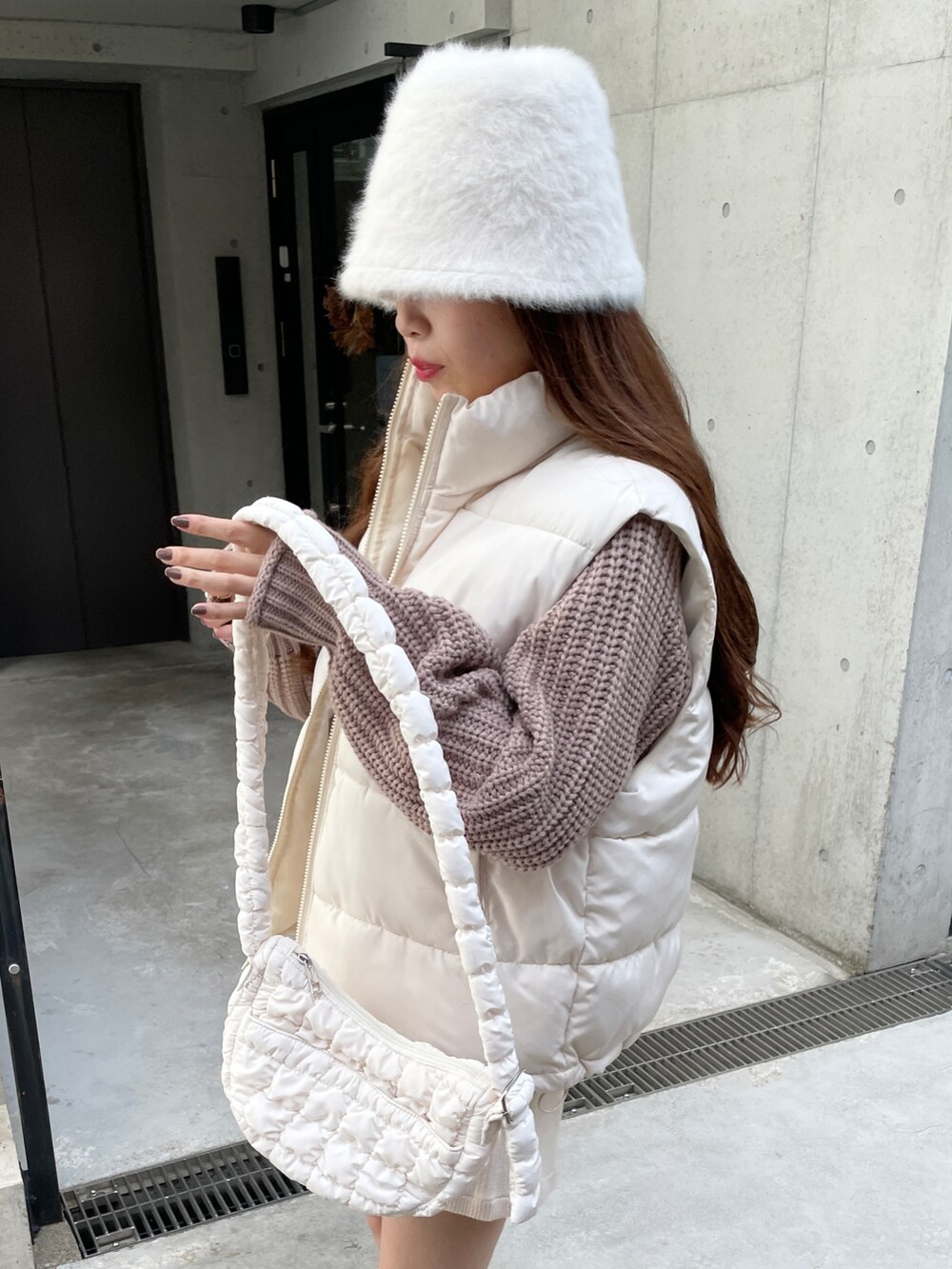 イエロー系のニット/セーター、ホワイト系のダウンベスト、ホワイト系のその他パンツを着用したレディースの秋コーディネートの4枚目の写真